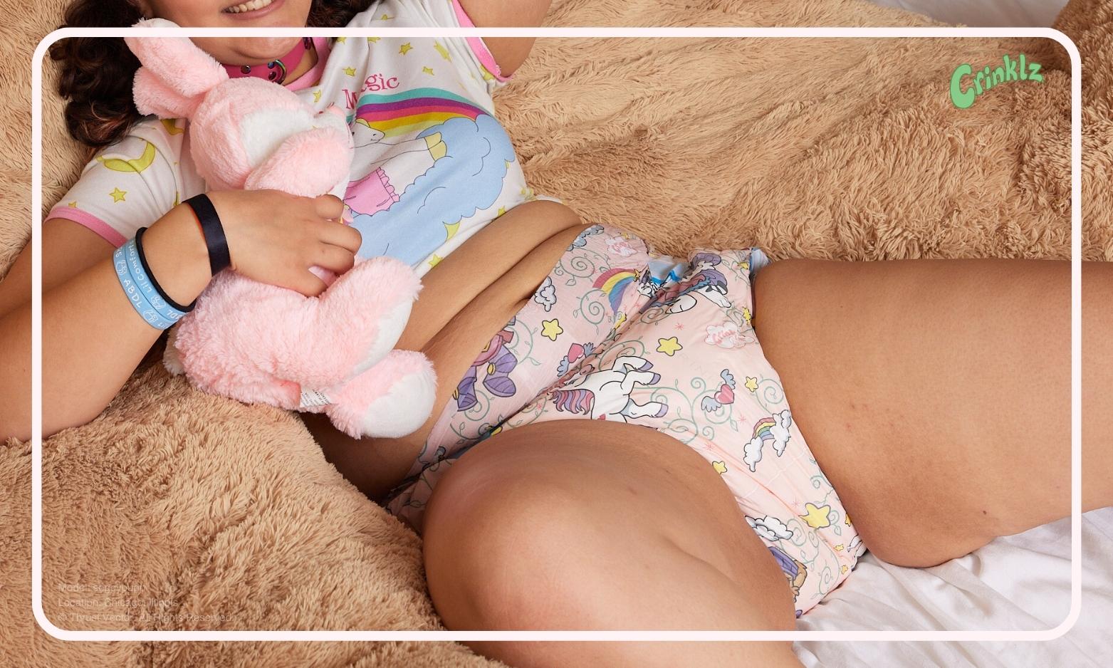 Soggypup wearing a Fairy Tale print diaper while lounging on a giant teddy bear. She's relaxing after a long day of play at CAPCon in Chicago, Illinois.