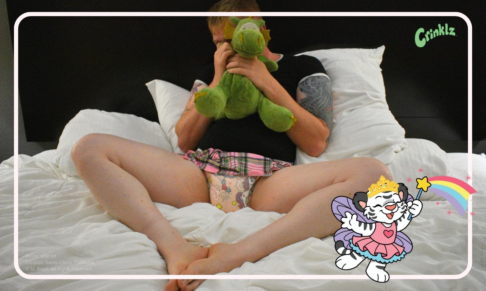 Tater Tot hiding behind a dragon stuffie wearing a Crinklz Fairy Tale print diaper in Los Angeles, California.